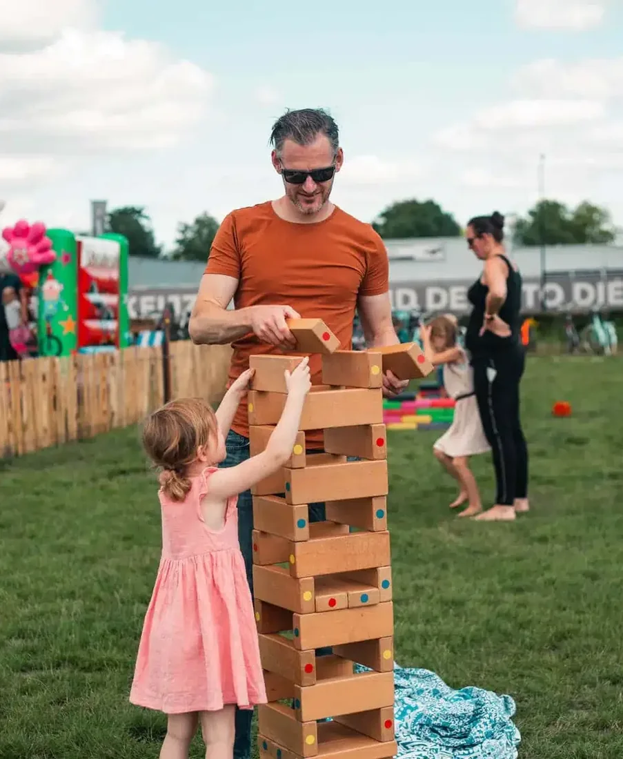 Vader en dochter bij de vallende toren voor een springkussen