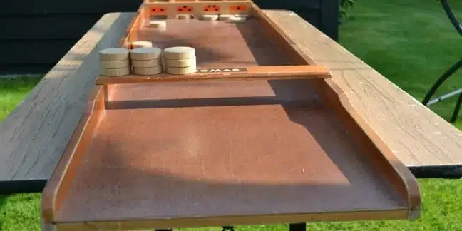 Sjoelbak op het gras, met de schijven op het bord