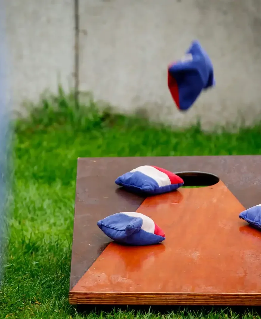 Cornholezakje vliegt naar het bord, twee zakjes liggen er al op