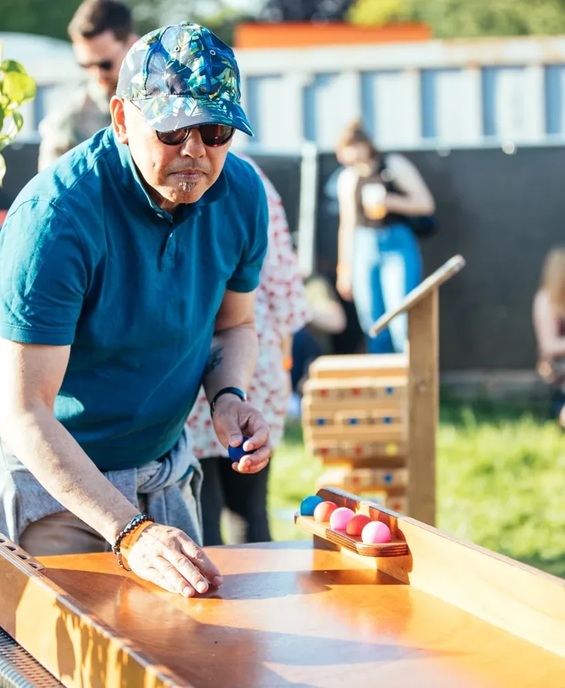 Man met pet mikt een bal op het ballenrolspel