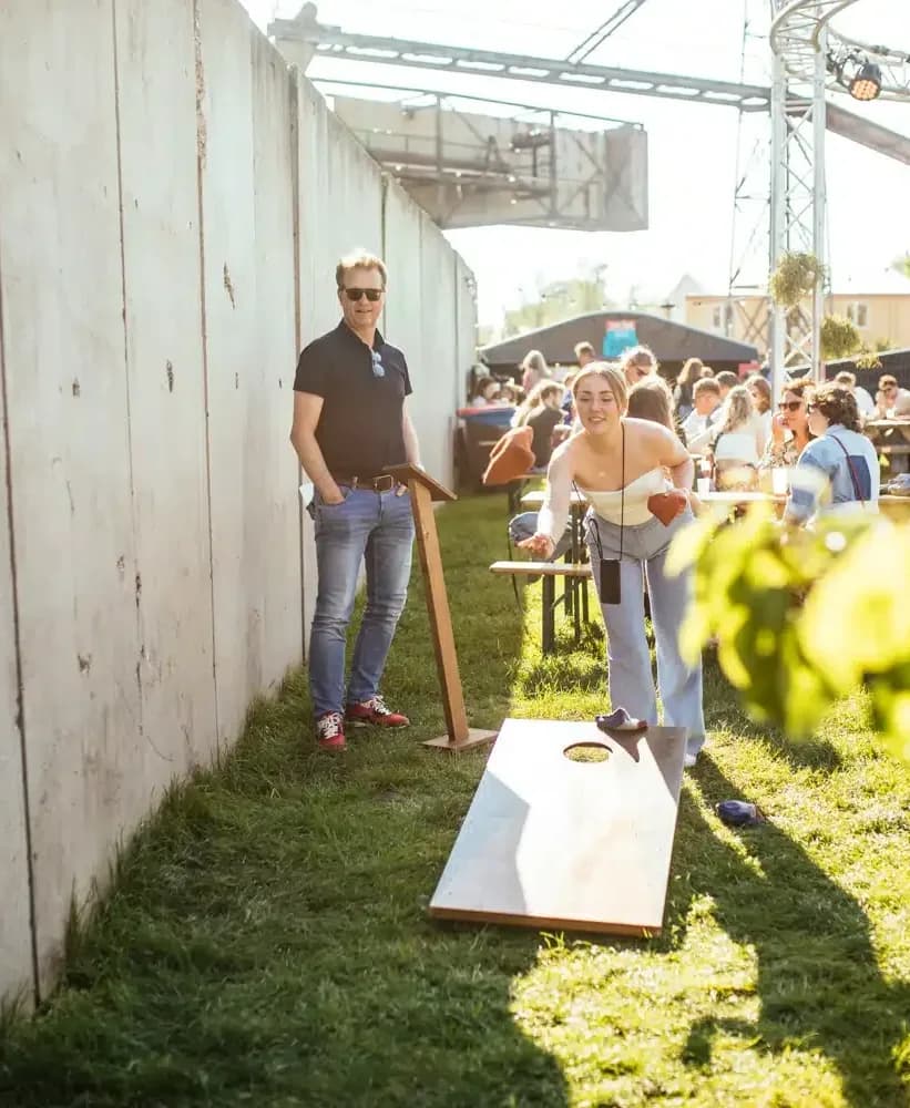 Man wacht zijn beurt af bij het cornholebord in de zon