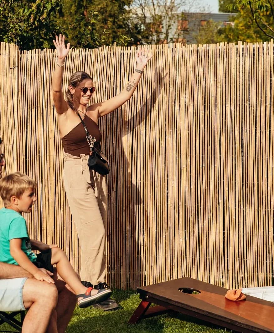 Vrouw juicht na een worp bij cornhole, een jongen kijkt toe
