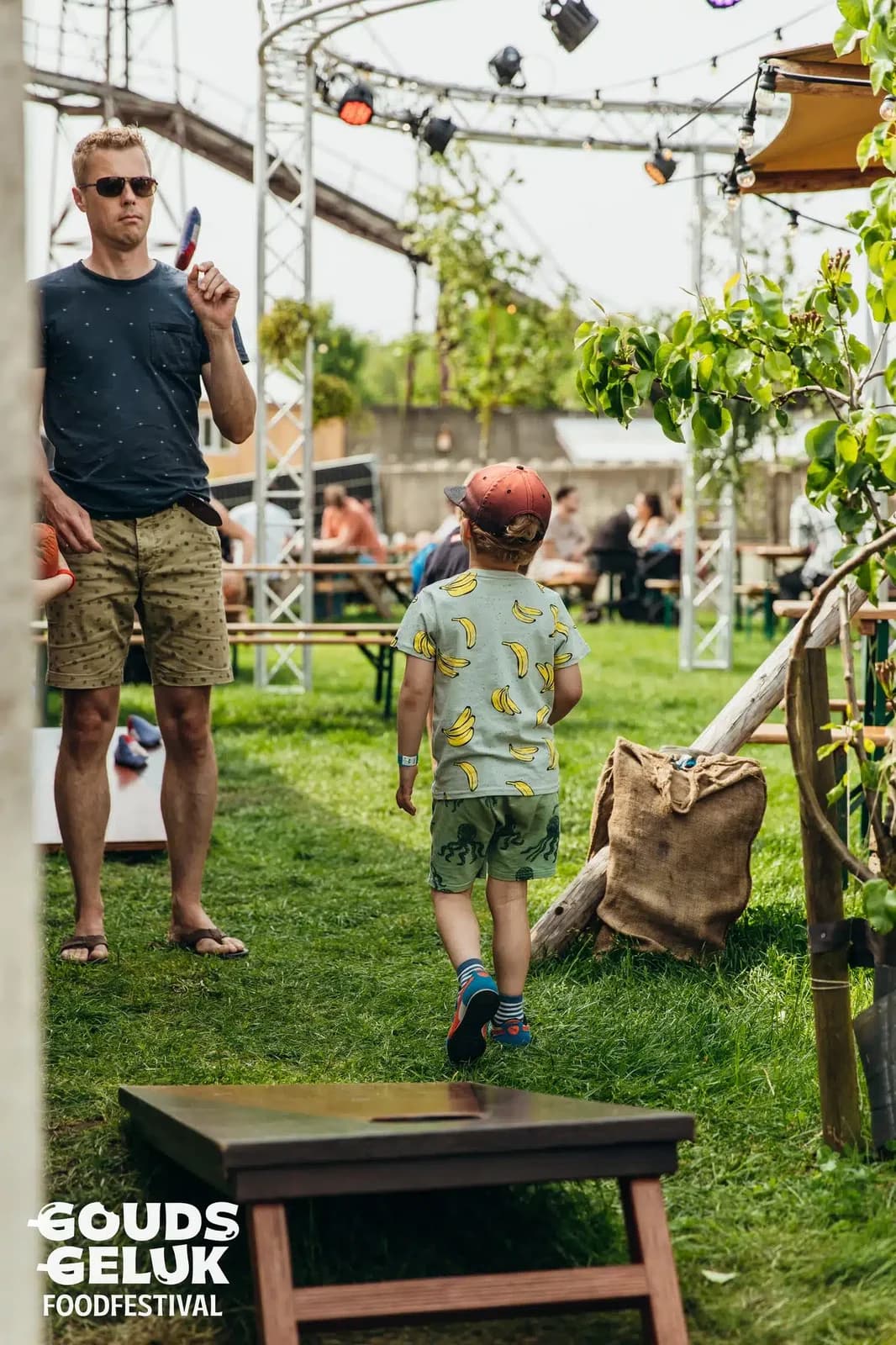 Vader en zoon lopen tussen de spellen op een festivalveld