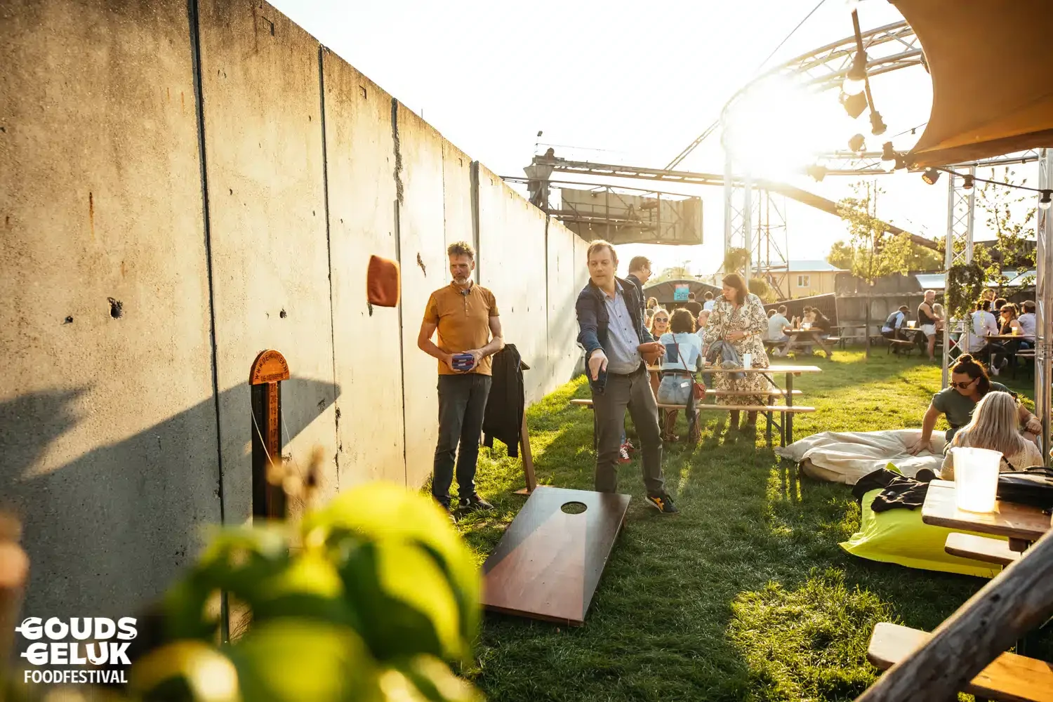 Cornhole op het gras tijdens een festival, met publiek op de achtergrond
